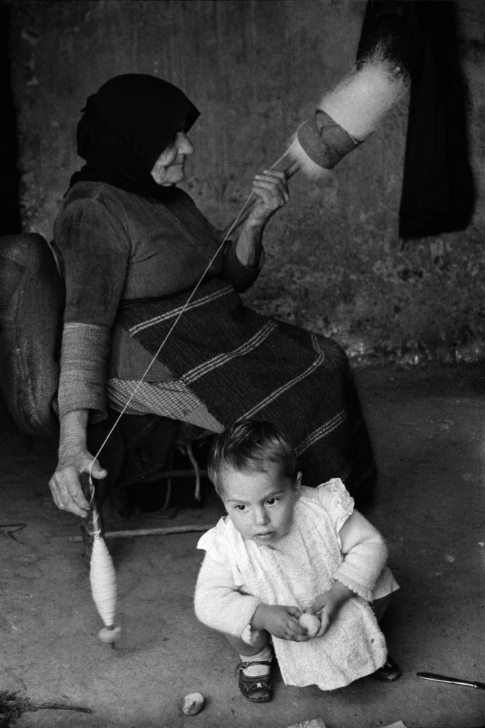 During his 1962-63 stay in Greece, Costa traveled to many villages that lacked electricity. He photographed this woman who sat in the doorway of her home in order to have the light needed to work and watch her grandchild.