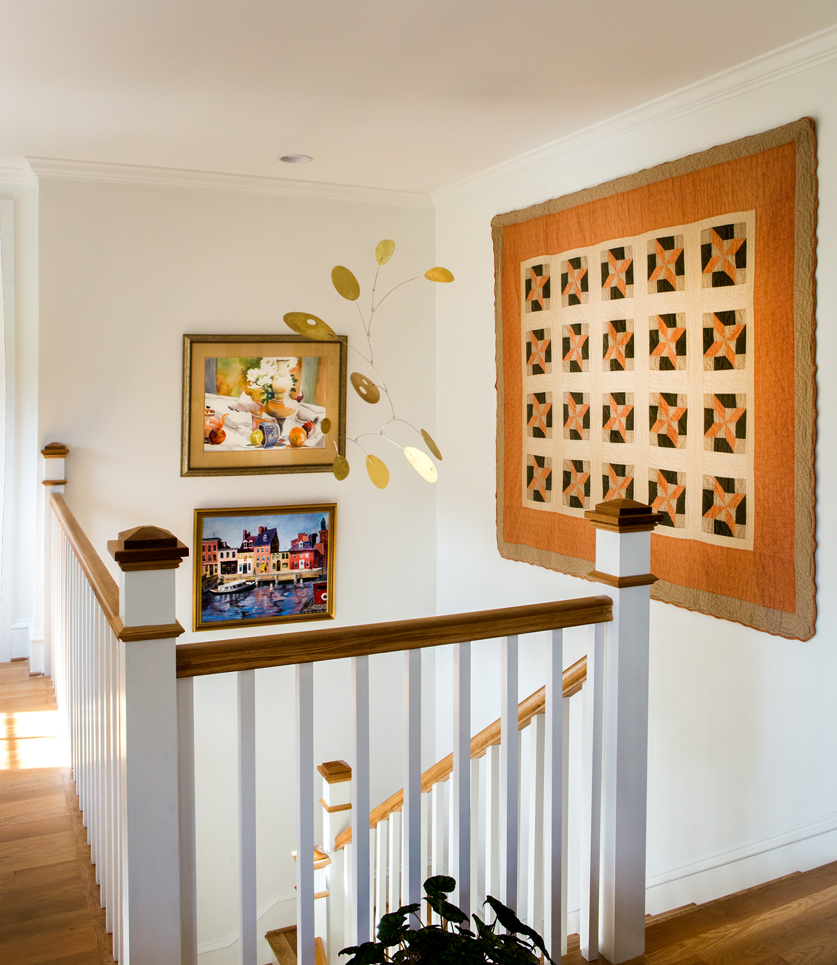 The upstairs stairwell has a warm feel with the addition of artwork and a quilt hanging on the walls as well as a mobile from the ceiling. Linda was deliberate in her placement of items, giving the space a three-dimensional spirit.