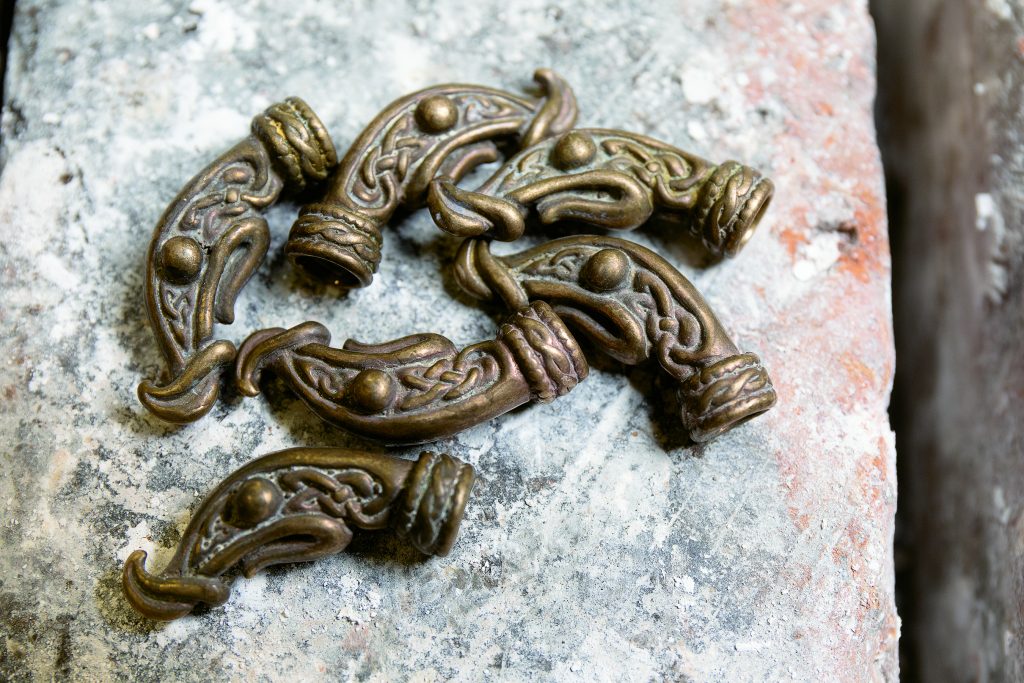 Newly cast bronze Viking dragon heads are ready to be put on the ends of Viking arm rings.