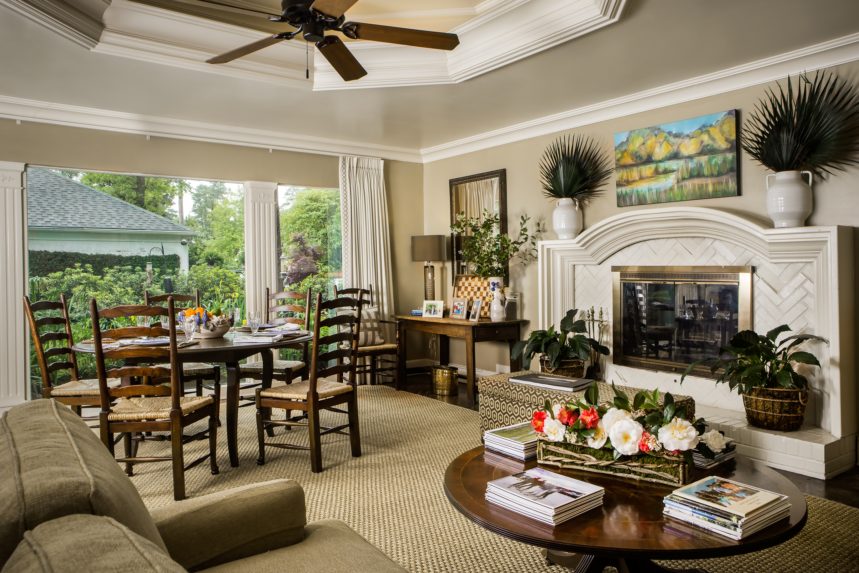 The family room off of the kitchen is central to the Folline family activities. The multipurpose room, previously a garage, looks out onto a lush garden planted by Lilla Hoefer. The fireplace is original to the home, and the arrangement of camellias is from the garden. 