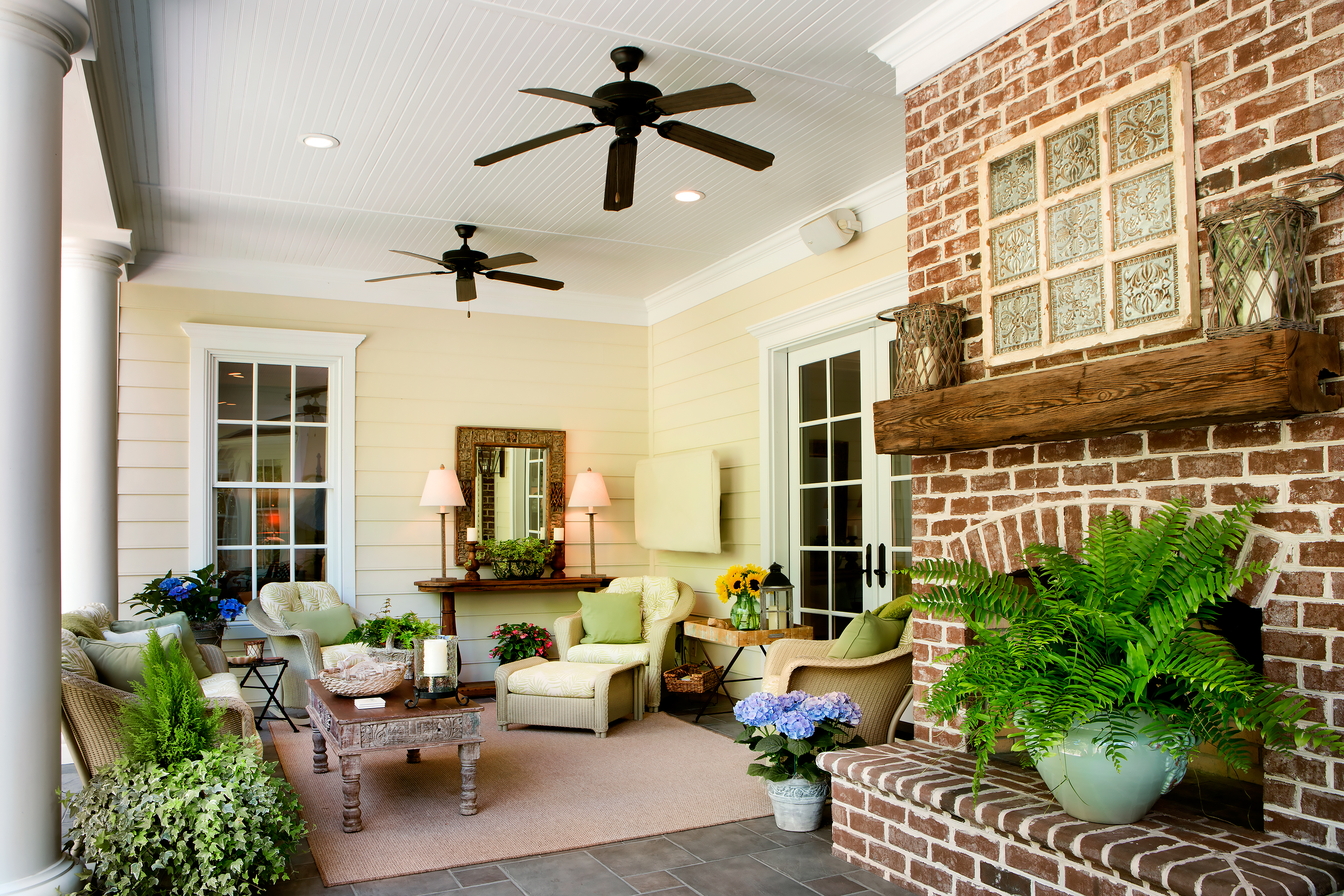Kathy and Chuck’s porch is a tranquil spot as well as a place for entertaining friends and family. Wicker seating and ceiling fans along with ivy, ferns, and geraniums give the seating area relaxed Southern charm.