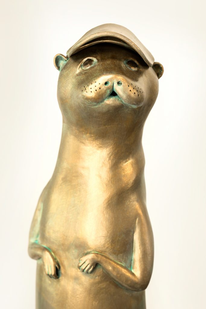 Pat Gilmartin’s otter piece, called “I Smell Something Fishy,” is one of her new clay works up for exhibition. The otter has the option of wearing the sporty baseball cap!