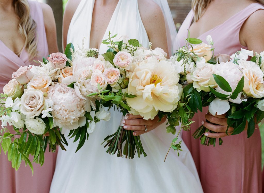 Large bouquets of lovely pink and white peonies with garden and spray roses amid greenery are perfect complements to the bridal party.