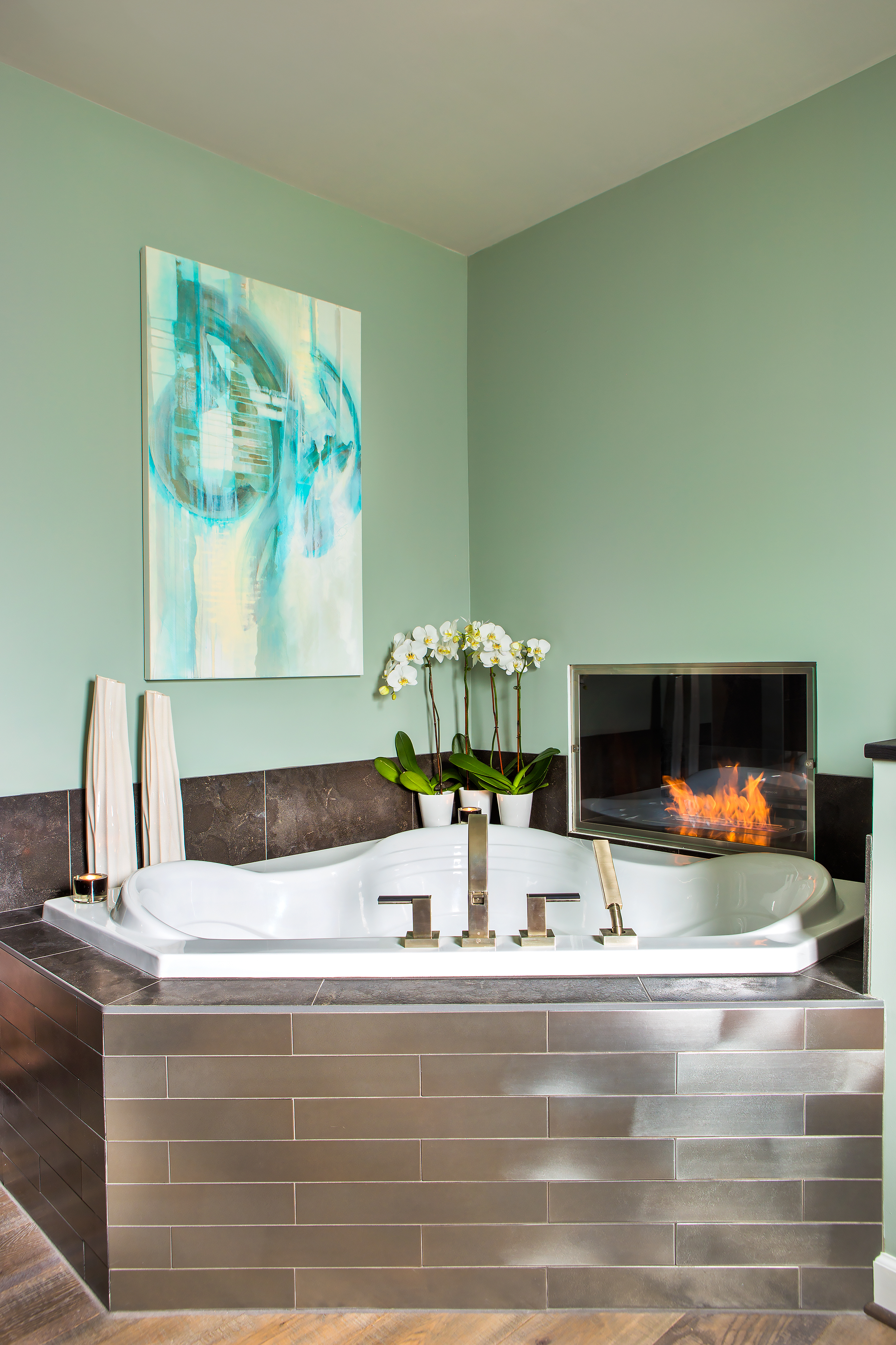 The gracious master bath tub shares a two-sided alcohol flame fireplace with the master bedroom. Dark gray ceramic and metallic tiles are from Palmetto Tile. The beautiful orchids are courtesy of The Fresh Market.
