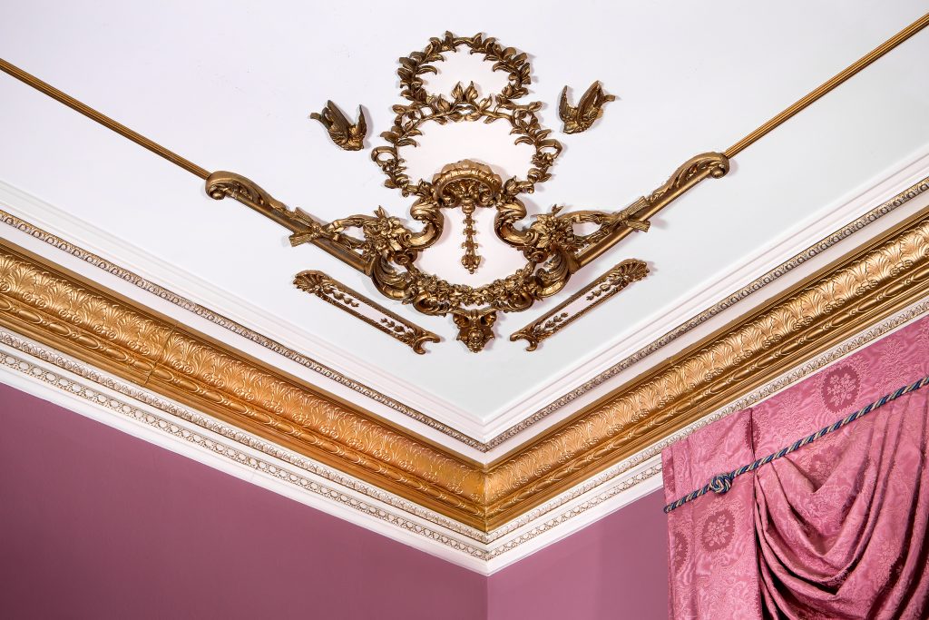  The decorative ceiling corner is adorned with a gilded shell cartouche of rose clustered festoons.
