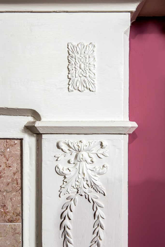 This fireplace detail has oak leaf medallions above intertwined olive branches with fruit and flower clusters. 