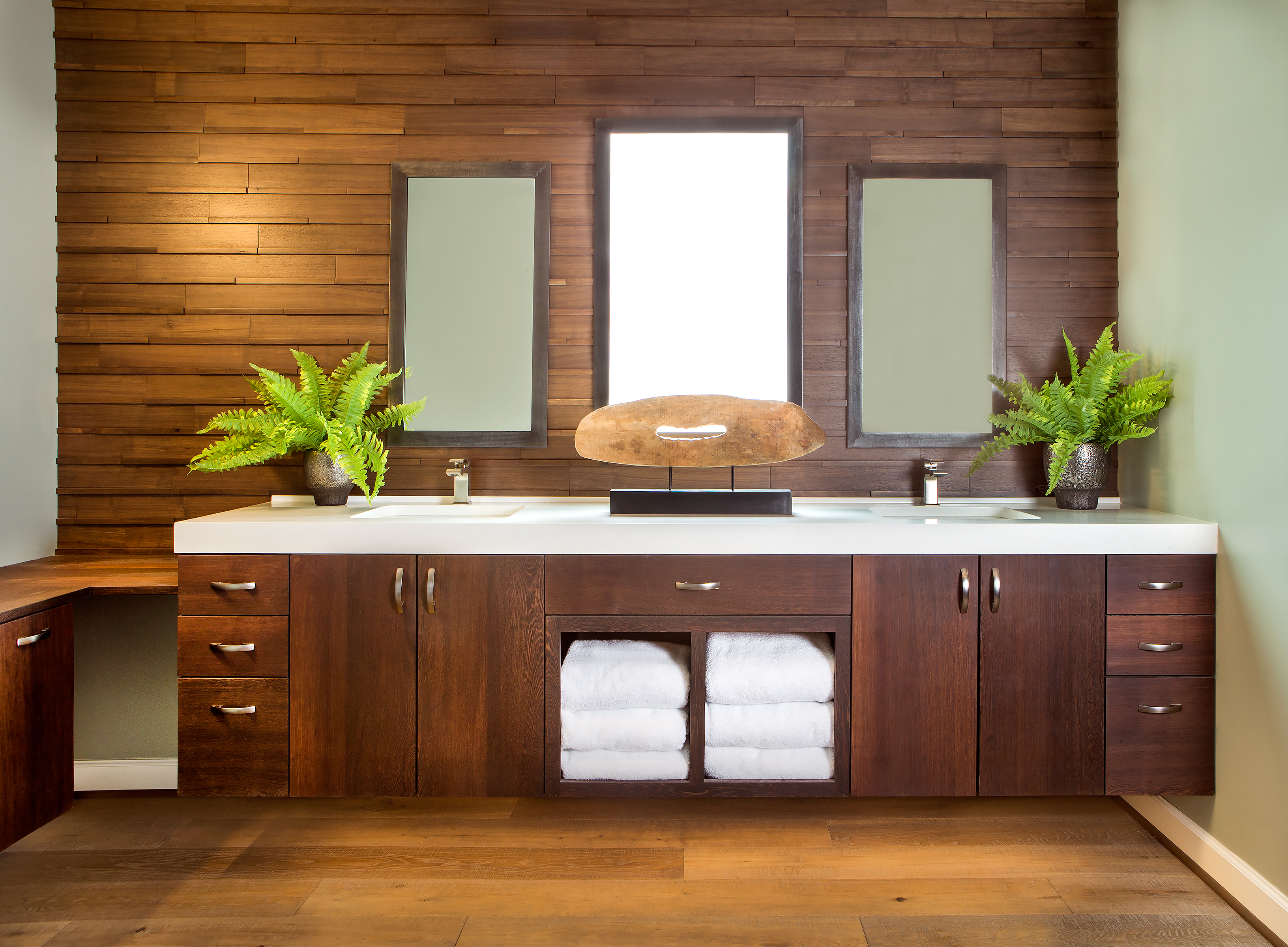 The master bath floating vanity was a collaboration of homeowner Paul Manning, designer Mandy Summers-Smith, and custom furniture designer Steven Fear. Constructed of natural wenge wood, which is resilient to stains, the overall feeling is elegant and masculine. The vanity mirrors are held in place by strong magnetic strips.
