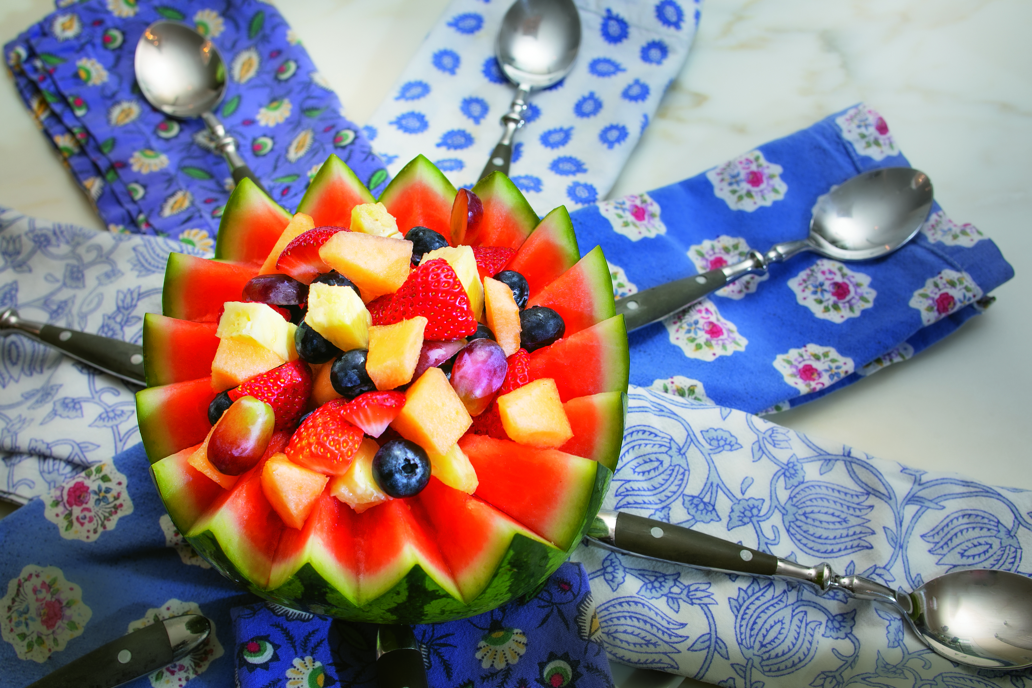 Fruit salad in a decorative watermelon gives a summer table refreshing style. Use a marker to draw a serrated border and carve carefully. Fill the cavity with your favorite berries and fruit and dress up your table.