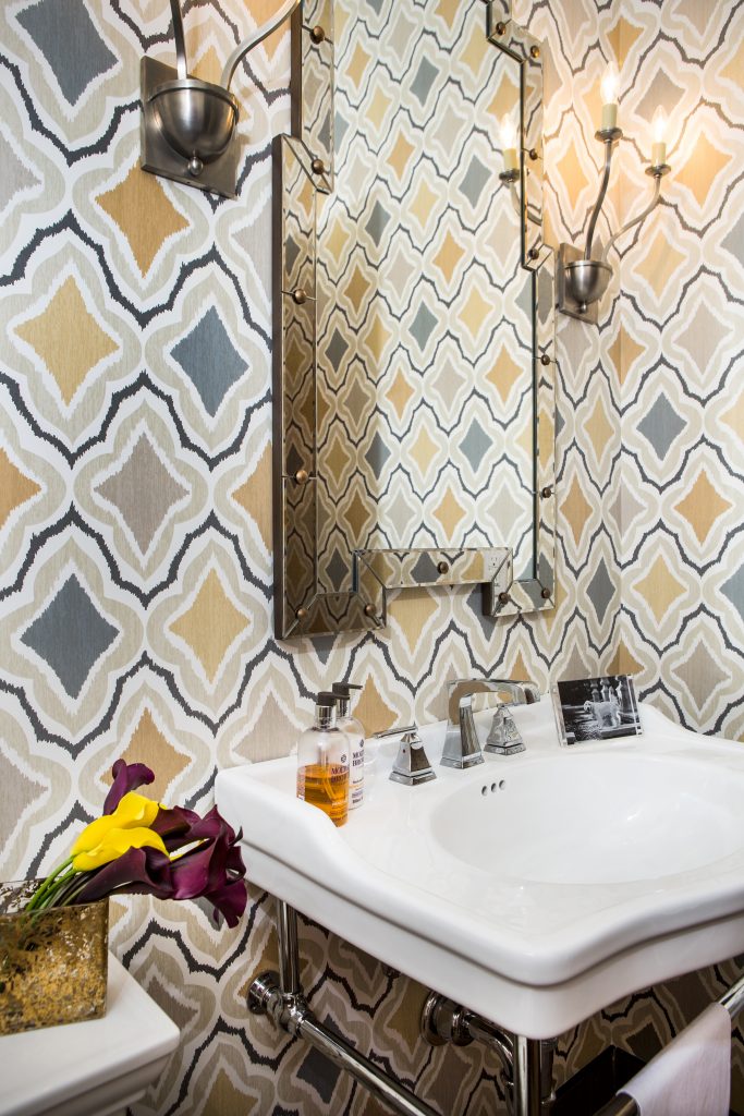 The powder room off the entrance hall is a creative design with traditional sink and contemporary wallcovering, mirror, and sconces.