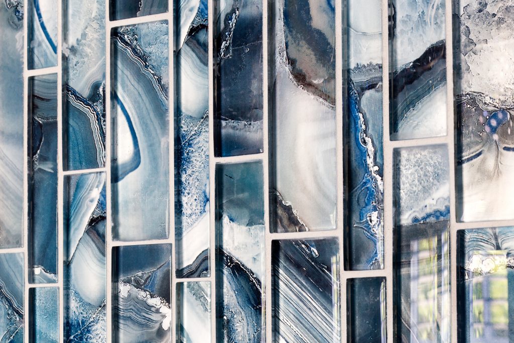 The tile in the waterfall feature strip showcases azure blue iridescent recycled glass.