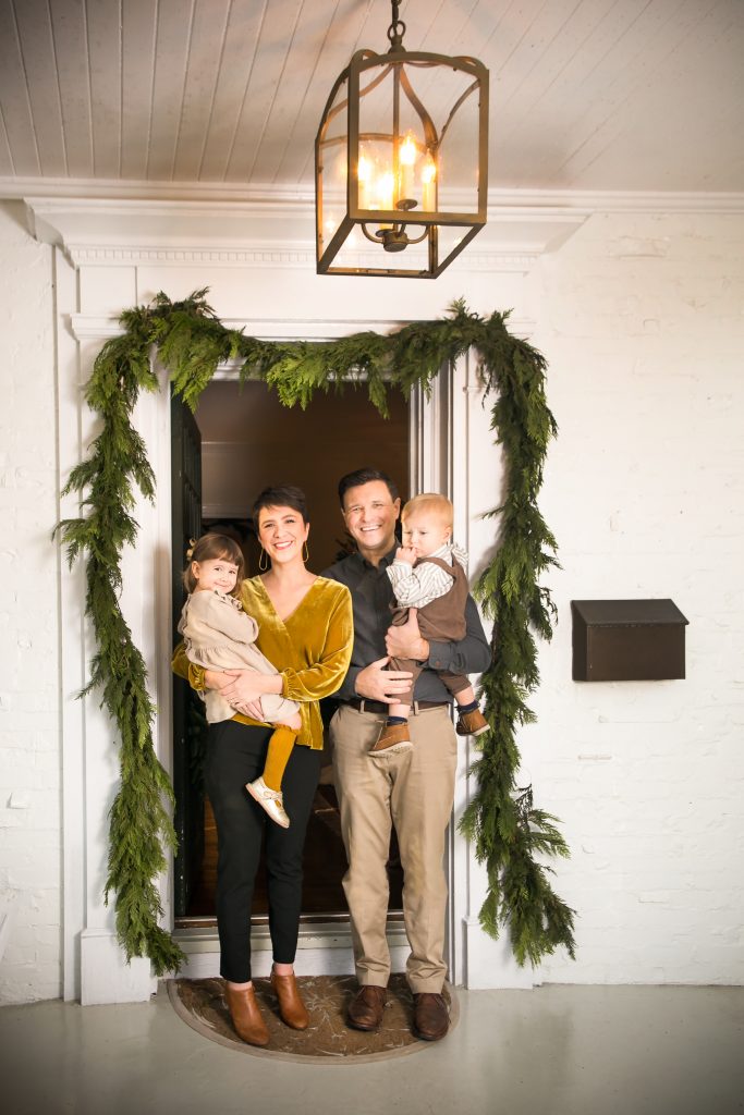  Jessica with Vivienne, 4, and Jim with Thomas, 2, dress their front door with garlands from the “Flower Truck” in Columbia.