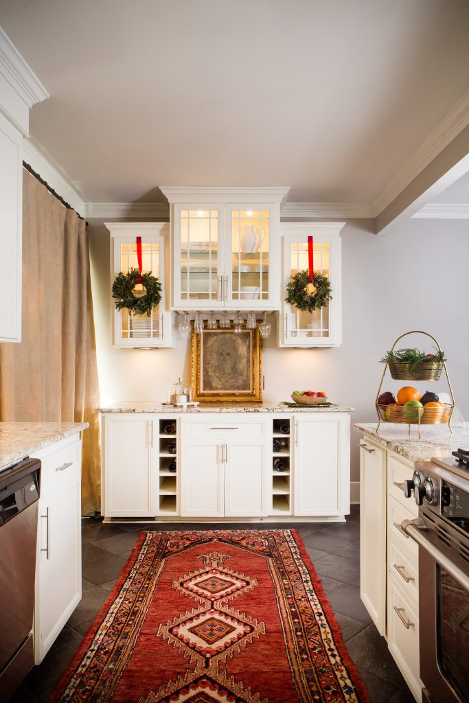 As a wedding planner, Jessica has access to an array of florals, but she chooses mostly greenery for the holidays. A pair of wreaths, hung with red velvet ribbons, accents the kitchen cabinetry.