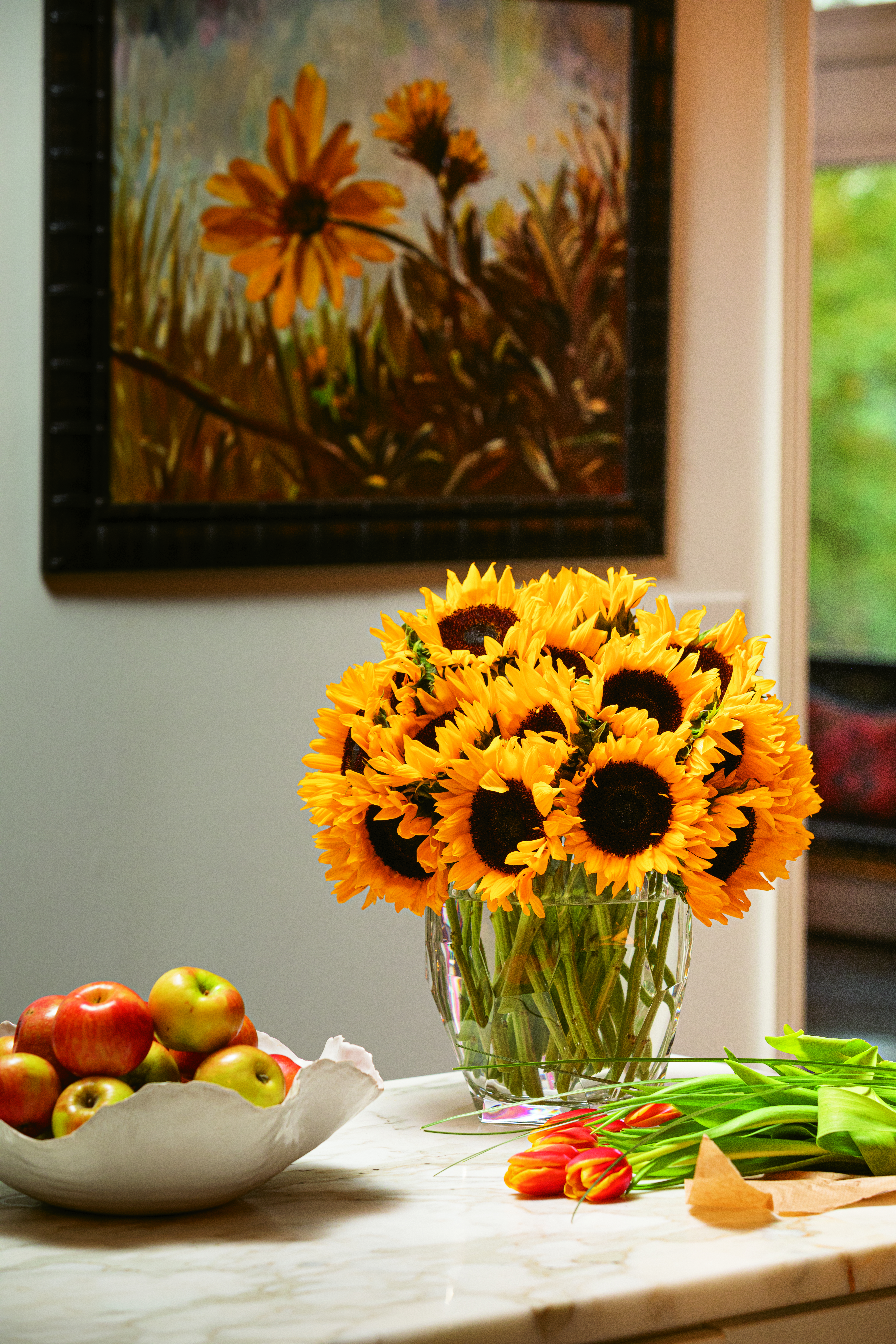 A wide mouthed wine bucket holds five bunches of glorious sunflowers. To build your arrangement, place the flowers one at a time around the rim of the vase in a spiraling fashion until you reach the top of the mound. Flowers courtesy of Trader Joe’s.
