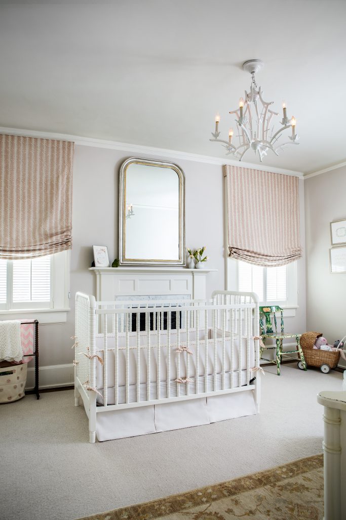 Baby Louise’s white Jenny Lind crib is accented by a sophisticated mirror over the mantel and vintage white bamboo chandelier. The antique quilt rack with handmade blankets and painted chair are cherished family pieces.