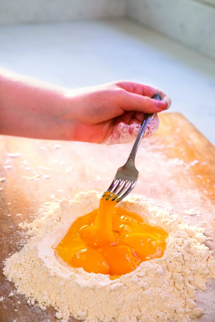 Use a fork to slowly whisk the eggs into the flour well. 