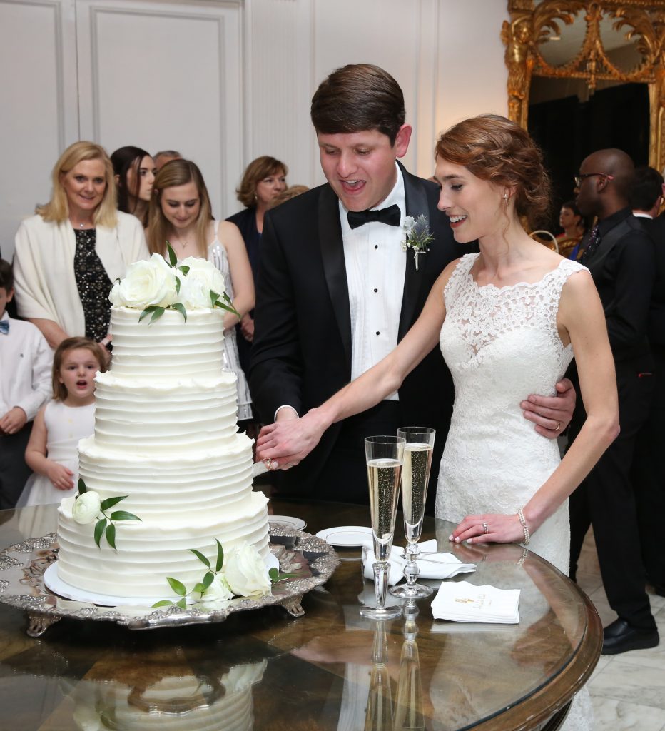 The wedding cake by Parkland Cakes is beautifully accented with white roses by Julianne Sojourner. The bride and groom toast with Taittinger Champagne in anticipation of a honeymoon in France. 
