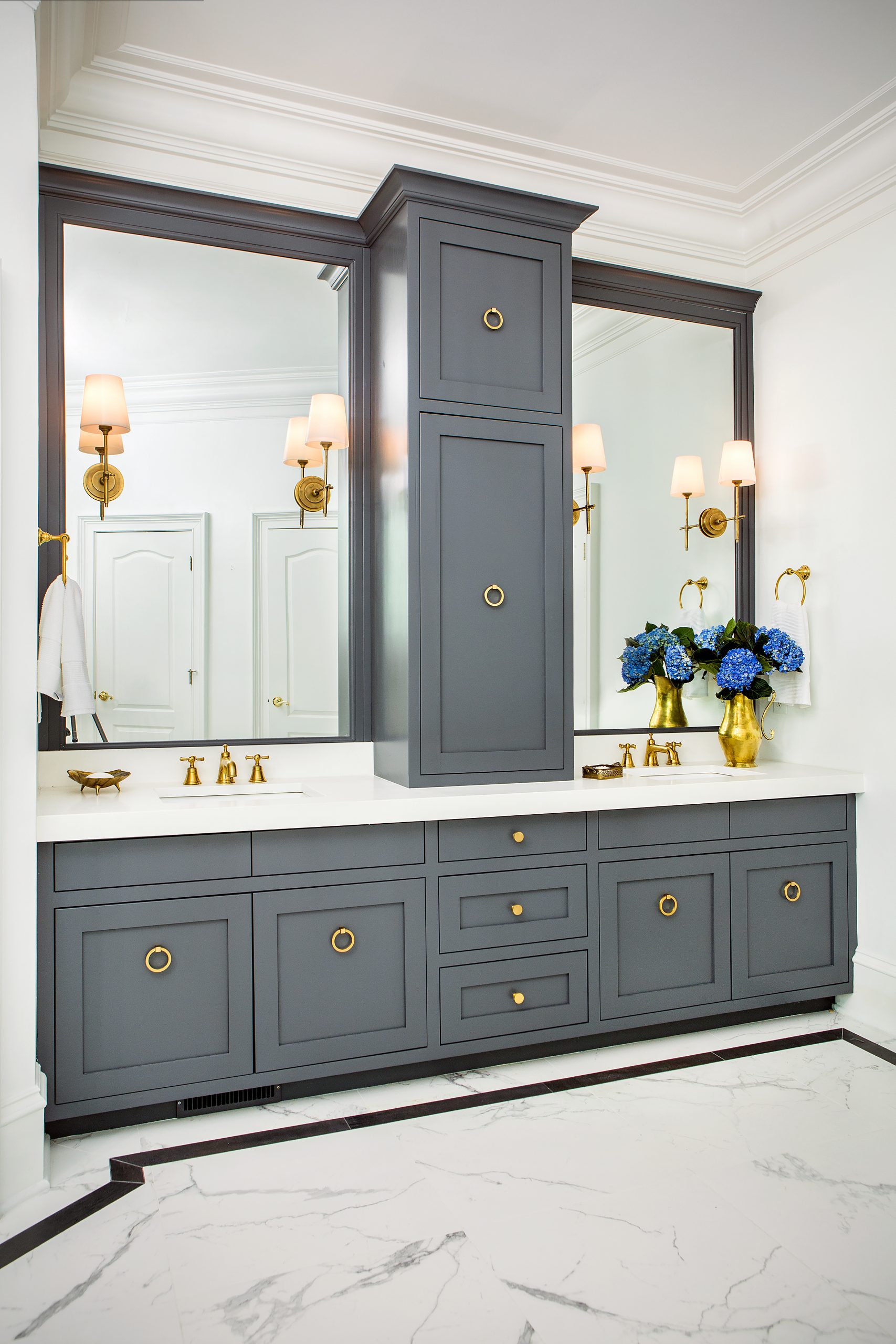 Veronica explains that the goal of the master bath renovation was providing built-in cabinetry to resemble furniture. This was accomplished with a white quartz vanity against the Sherwin-Williams Peppercorn cabinets, accented by stylish brass pulls and sconces installed directly into the mirror.
