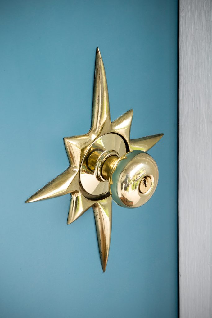  The Scullions replaced the original front door with a solid door painted a custom shade of teal to showcase the shiny starburst escutcheon knob repurposed from a neighbor. 