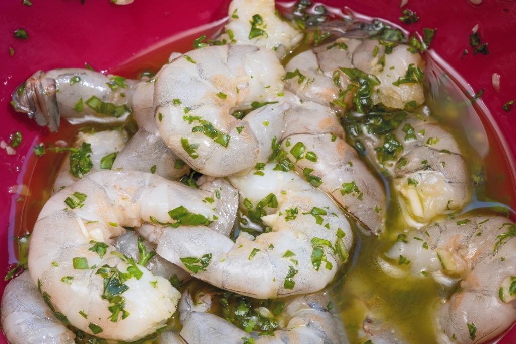  Chop basil, parsley, and garlic together, allowing the flavors to begin integrating. Whisk the herb mixture into olive oil and marinate the shrimp for 30 minutes to two hours for flavors to heighten before grilling.