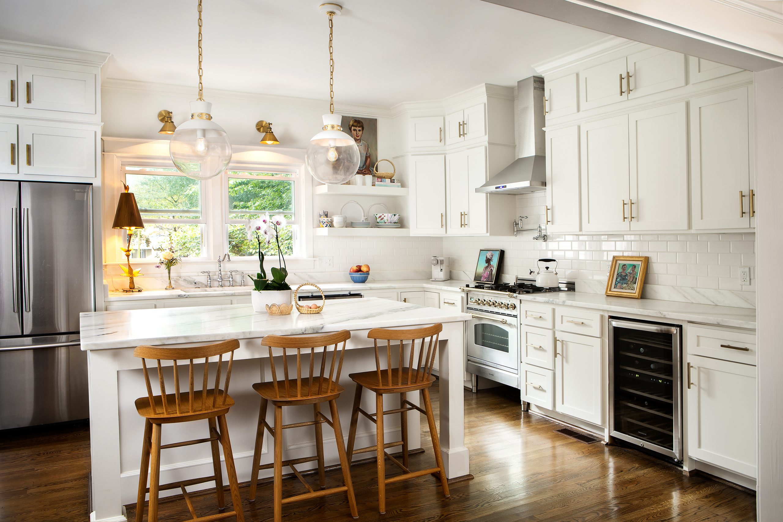 Preserving history and their budget, AnnaBelle used existing cabinetry in the kitchen, replacing doors and hardware. Art and lighting, along with the stainless steel and brass Italian range by Hallman, are beautiful accents.