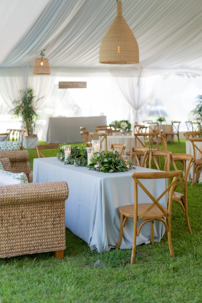 The reception venue was an oasis inside of the tent. Custom-made green and white Exchange toile was accented by candles, lush green and white flowers, wicker seating areas, cafe tables, and blue velvet upholstered ottomans. 
