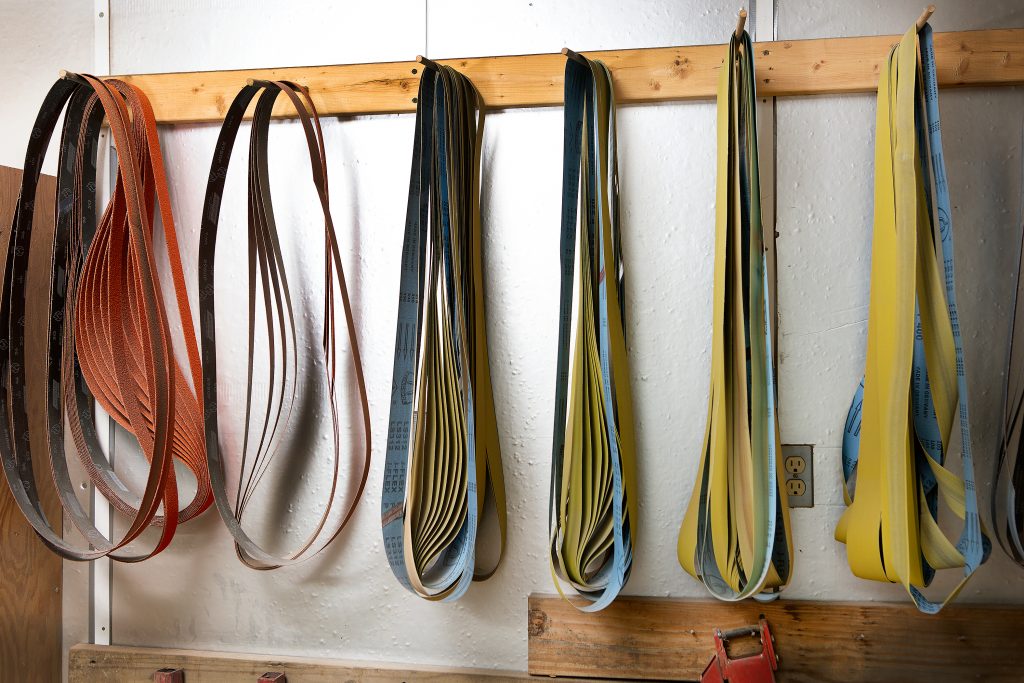 Different sizes and levels of sanding belts are used to shape and polish the blades and handles of knives. 