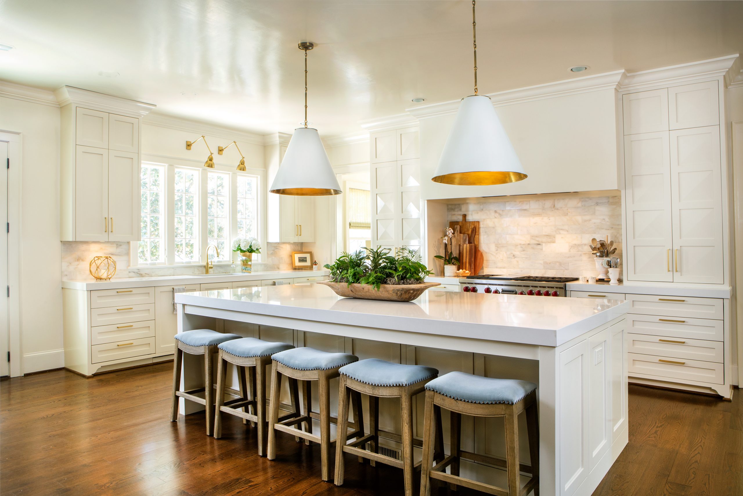 The kitchen is the heart of the home and the place where the Kays enjoy cooking and parties with friends and family. Gold toned hardware shines against white custom cabinetry, with a Calacatta marble backsplash and floor to ceiling symmetrical cabinets.