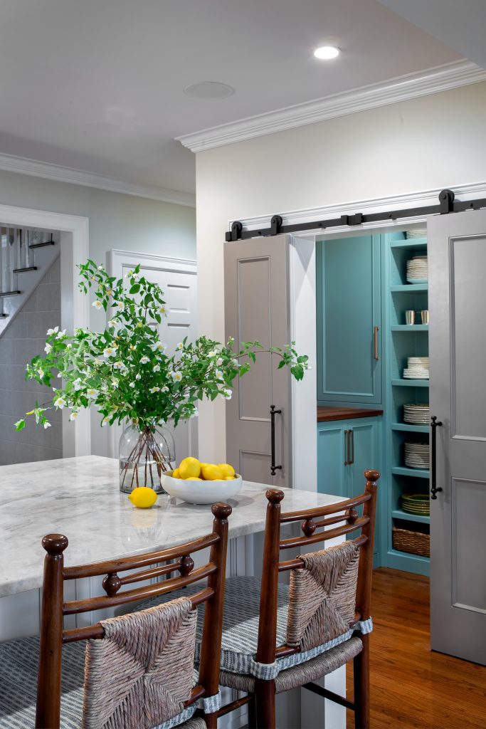  The dish pantry painted in Farrow and Ball Dix Blue is an elegant addition that opens to the kitchen by sliding barn doors. Mock Orange arrangement by Cricket Newman Designs. 
