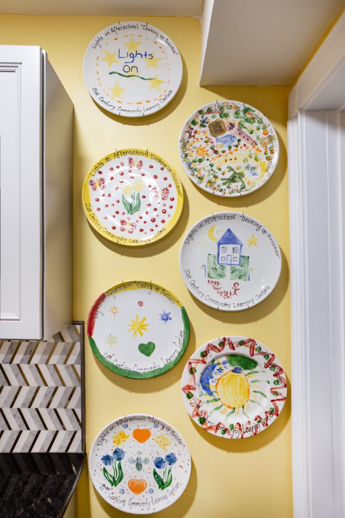 To the right of the kitchen cabinets is a collection of ceramic, hand-painted plates commemorating seven years of after-school programs organized by Sarah, a devoted middle school teacher.