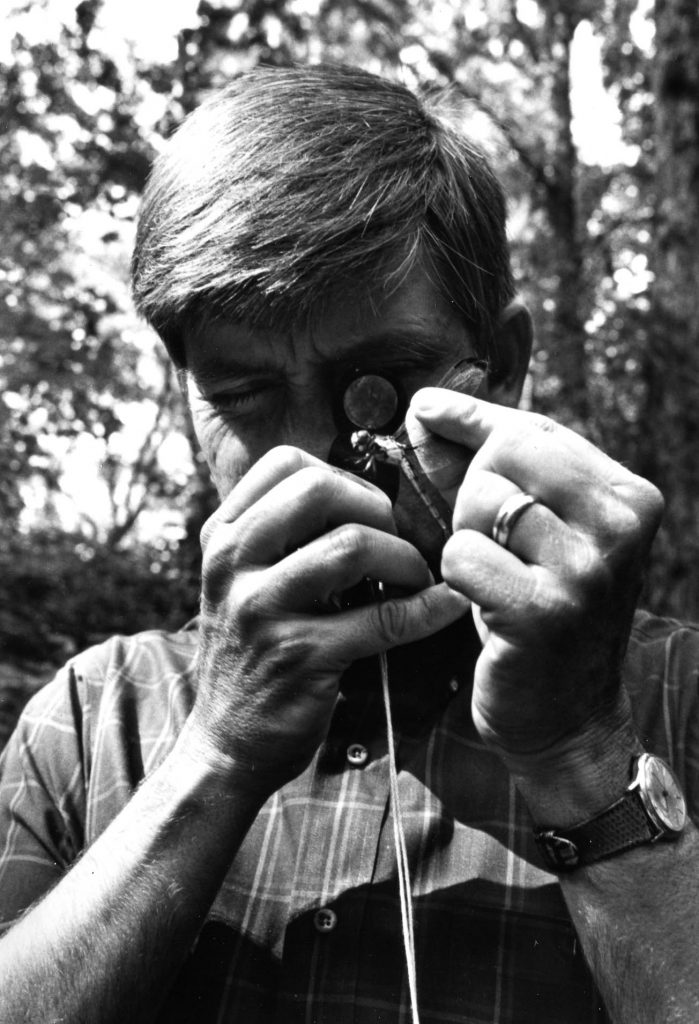 Rudy examining a dragonfly through a magnifying glass.