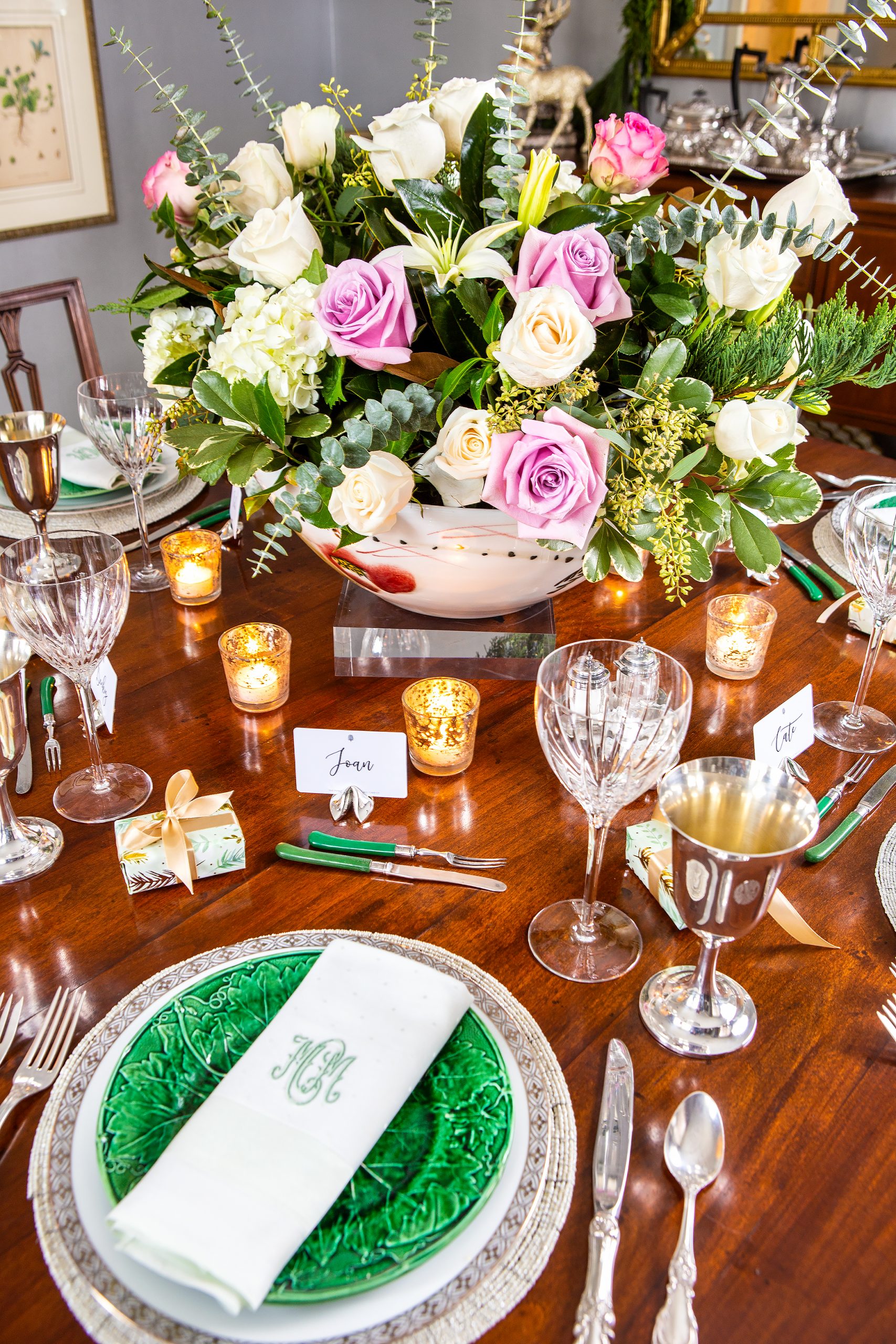 Catherine and Hank Mabry set two tables at Christmas, one in the dining room and one in the entrance hall. Using nontraditional colors, Catherine starts with a set of antique monogrammed napkins on a majolica plate and a gorgeous arrangement of roses and lilies. She uses her grandmother’s silver wine goblets and sprinkles around small wrapped boxes that her family call “phantom circes.” 