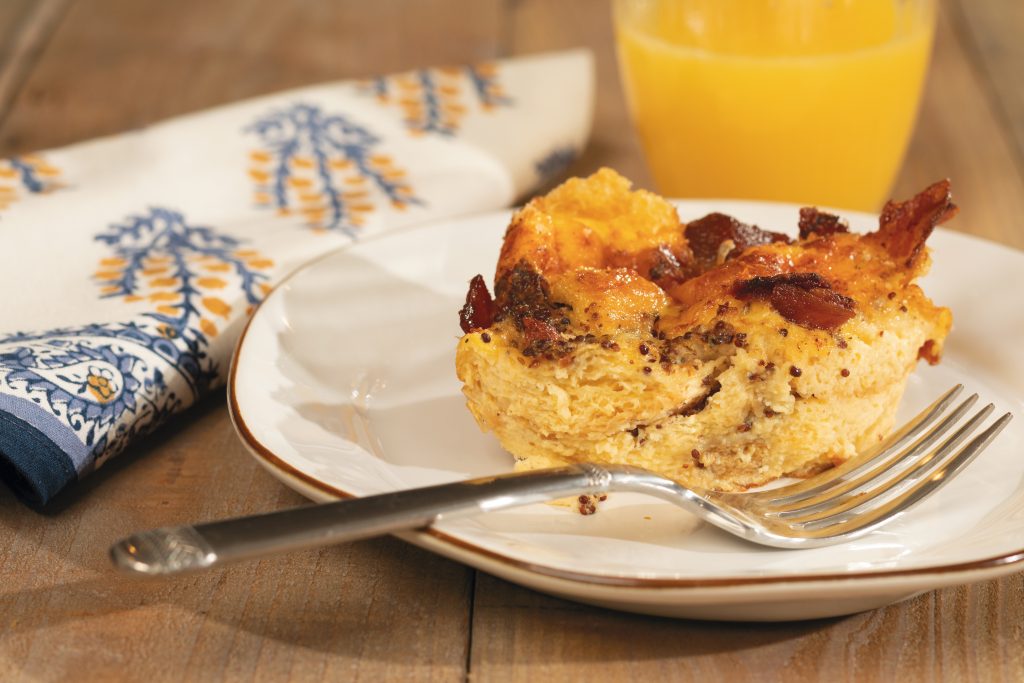  The Bacon and Swiss Cheese Strata from Nathalie Dupree’s Comfortable Entertaining is best when mixed a day before baking. The dish can be baked in a large casserole, individual ramekins, or muffin cups. Contaria Skyros Designs plate, Casafina Sensa juice glass, Pomegranate sugar blue & marigold napkin, Juliska flatware, and bamboo serving set courtesy of Cottage & Vine.
