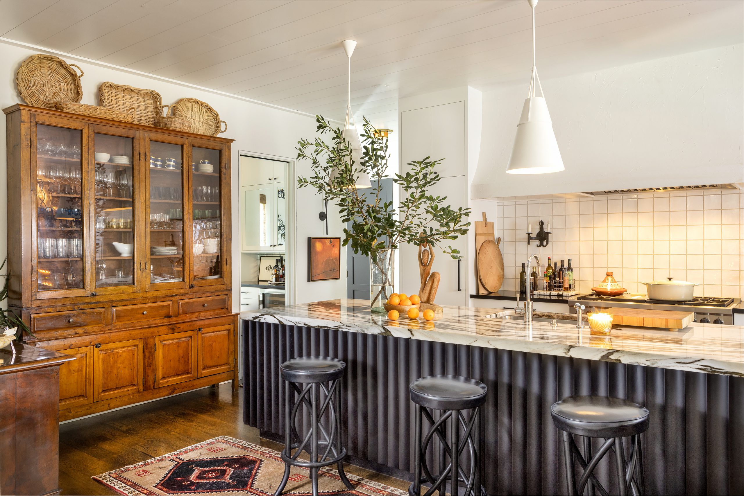 A 13-foot island without an overhang is topped with quartzite, a stone that Ford says presents more options than in years past. The material for the rest of the kitchen counters is black Corian, which she likes because it is soft to the touch. The furniture includes treasured finds Ford and George have collected through the years. 