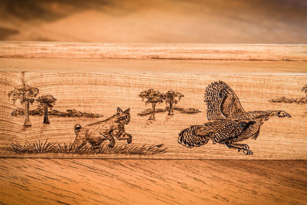 Artwork on Tanner’s “Hot Pursuit” ancient cypress box call by wood burning artist Ann Page.