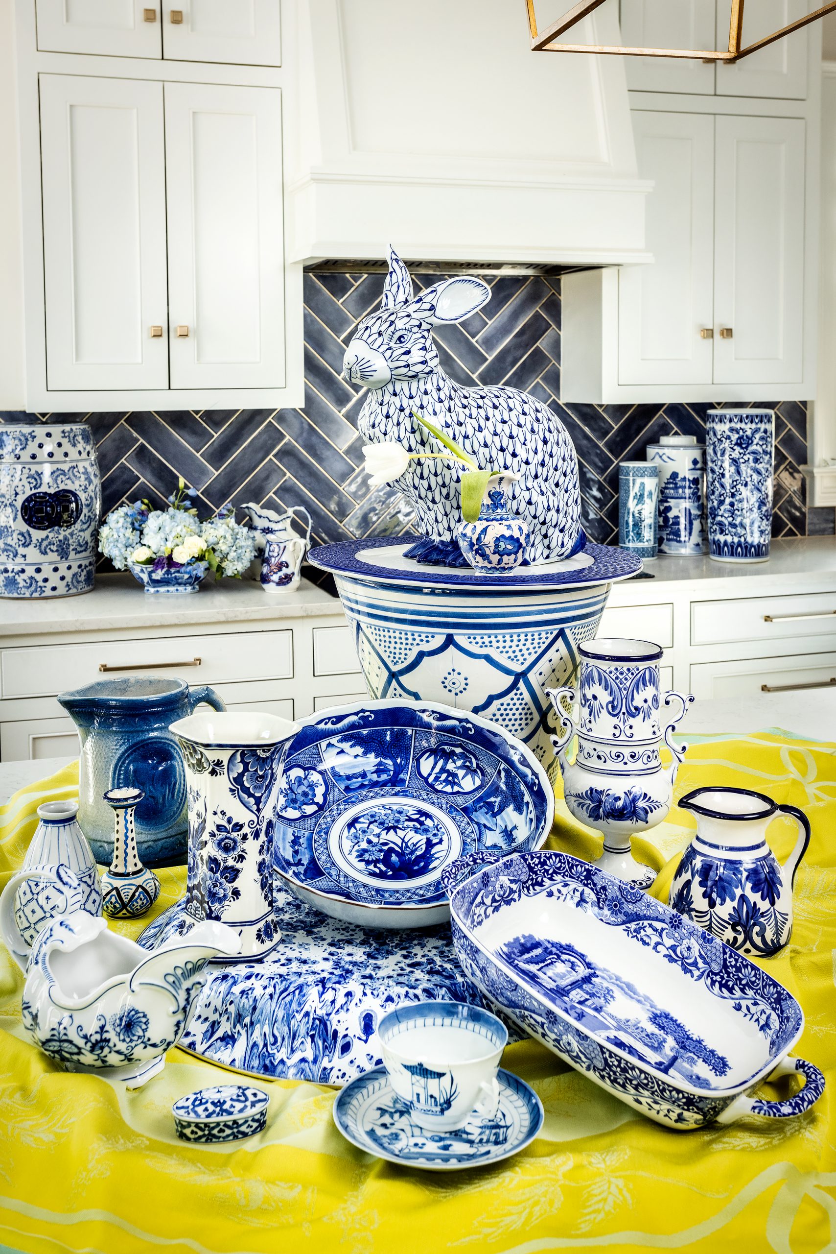 Blue and white pottery was first introduced in China in the 600s during the Tang dynasty and since then has made its way around the world in a myriad of different styles. Going clockwise, the small vase with the white tulip is from Iznik, Turkey; cylindrical vase, Mexico; small pitcher, Spain; Spode casserole dish, England; Export Canton tea cup and saucer, China; Onion Meissen gravy boat, Germany; diamond and striped vase, Japan; thin-neck vase, Iznik, Turkey; Saltware pitcher, America; hexagonal Delft vase on top of splatterware tray, the Netherlands; bowl in the middle, Japan; flower container in the back, Morocco; Tiffany & Co. plate, America; and the bunny is “modern Chinese export.”