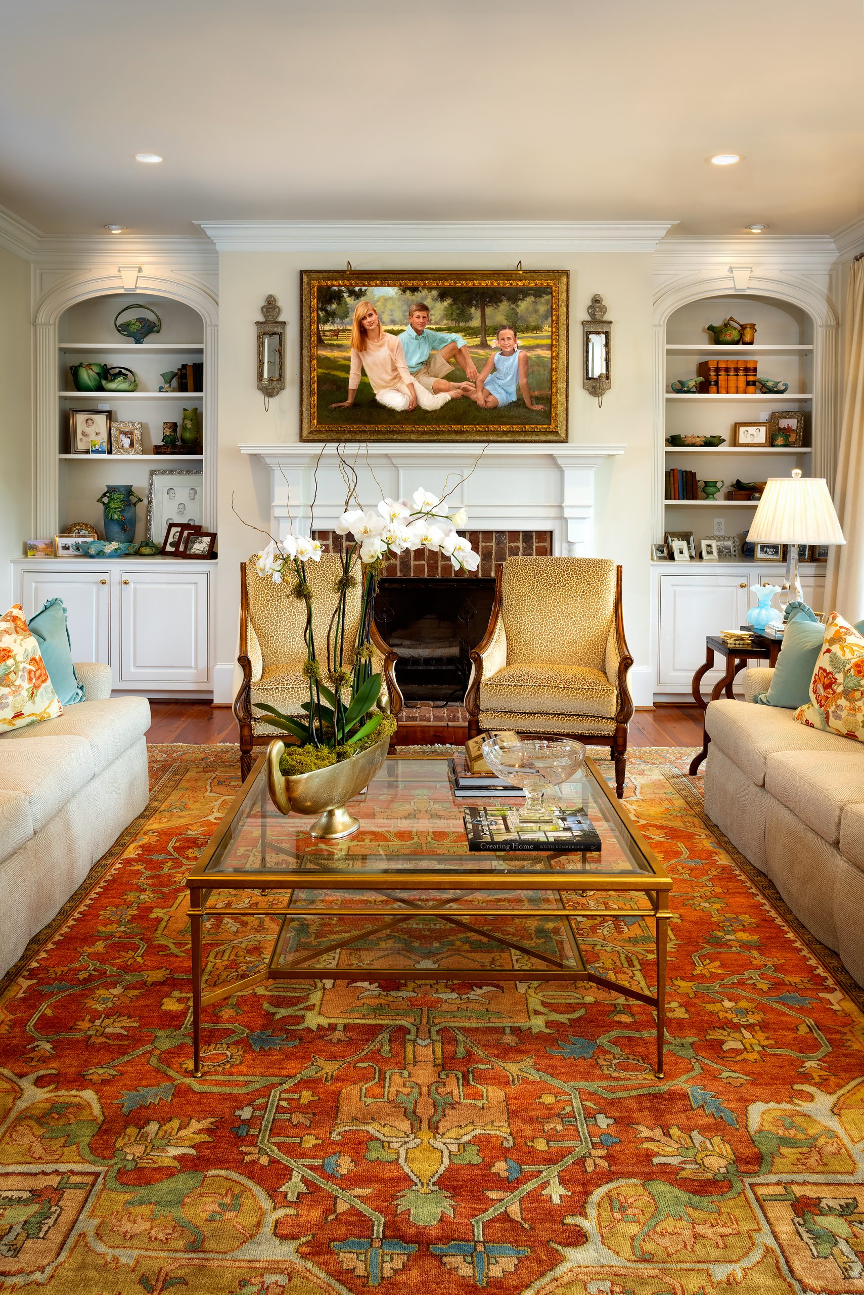 The Rhineharts’ living room is filled with natural light. It is anchored by a large dark apricot and gold rug laced with cream, blue, and green, which forms the color palette for the home. Above the fireplace is a portrait of their children, Gabbie, Hamilton, and Ellie, along with Sammee, the horse the children took care of when they were younger. Kelli credits Darby Schroder, her interior designer, for the cohesiveness of the color scheme throughout the house. 