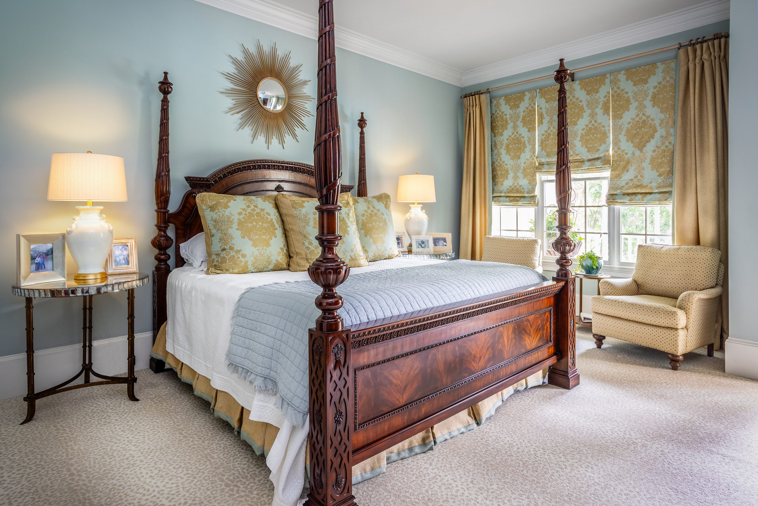 The serene blue and gold master bedroom rests on a cream leopard print carpet. A comfortable seating area is backed by windows overlooking the backyard, and the room has its own private door to enjoy the back porch. 