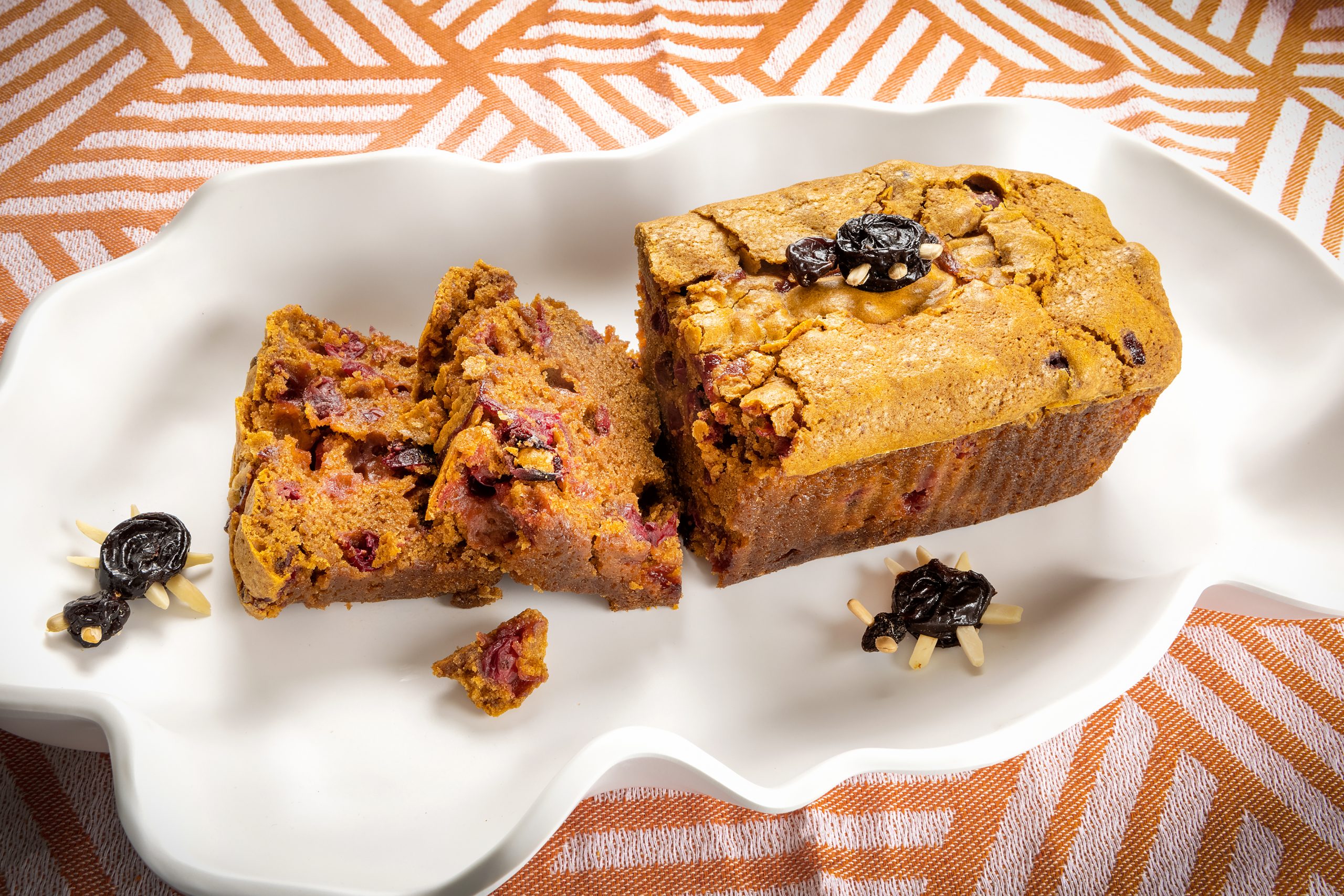 The tart and sweet pumpkin cranberry loaves are embellished with spiders made out of raisins and sliced almonds — this recipe is a family secret! Luxury Melamine dish by Beatriz Ball and Scents & Feel cloth, courtesy of Cottage & Vine.