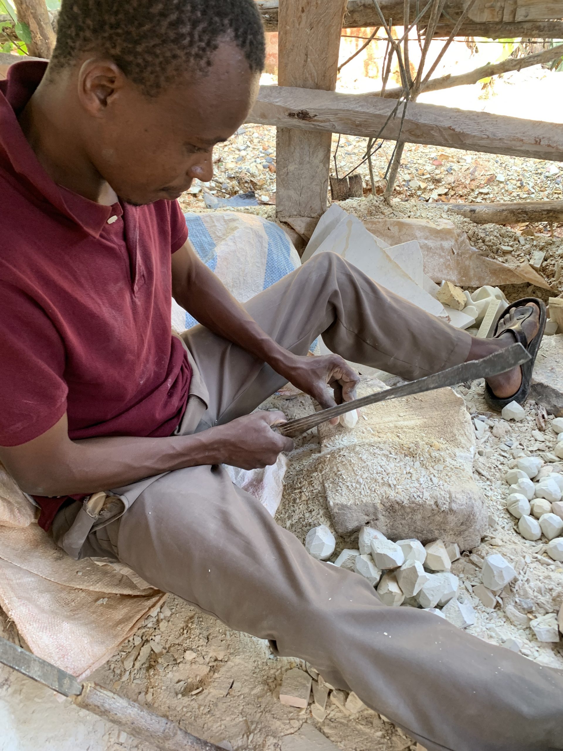 A soapstone artisan carves a heart with a machete, which they use to carve all products.
