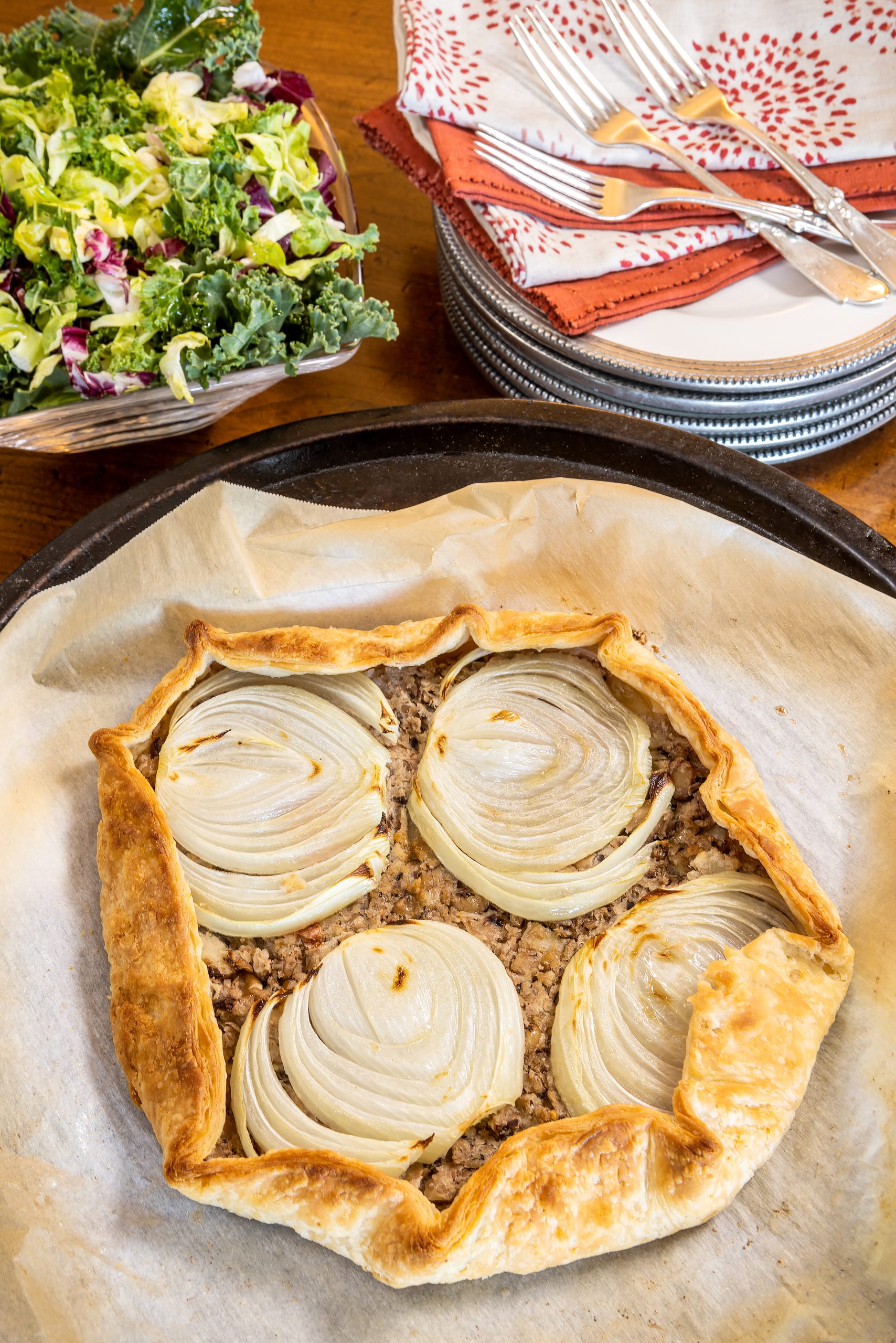 The delicious Black-Eyed Pea Galette, prepared with pancetta and garlic confit, is finished with thinly sliced onions baked on top. Creative Co-op red print and Be-Home Sedona napkins courtesy of Kudzu Bakery & Market.