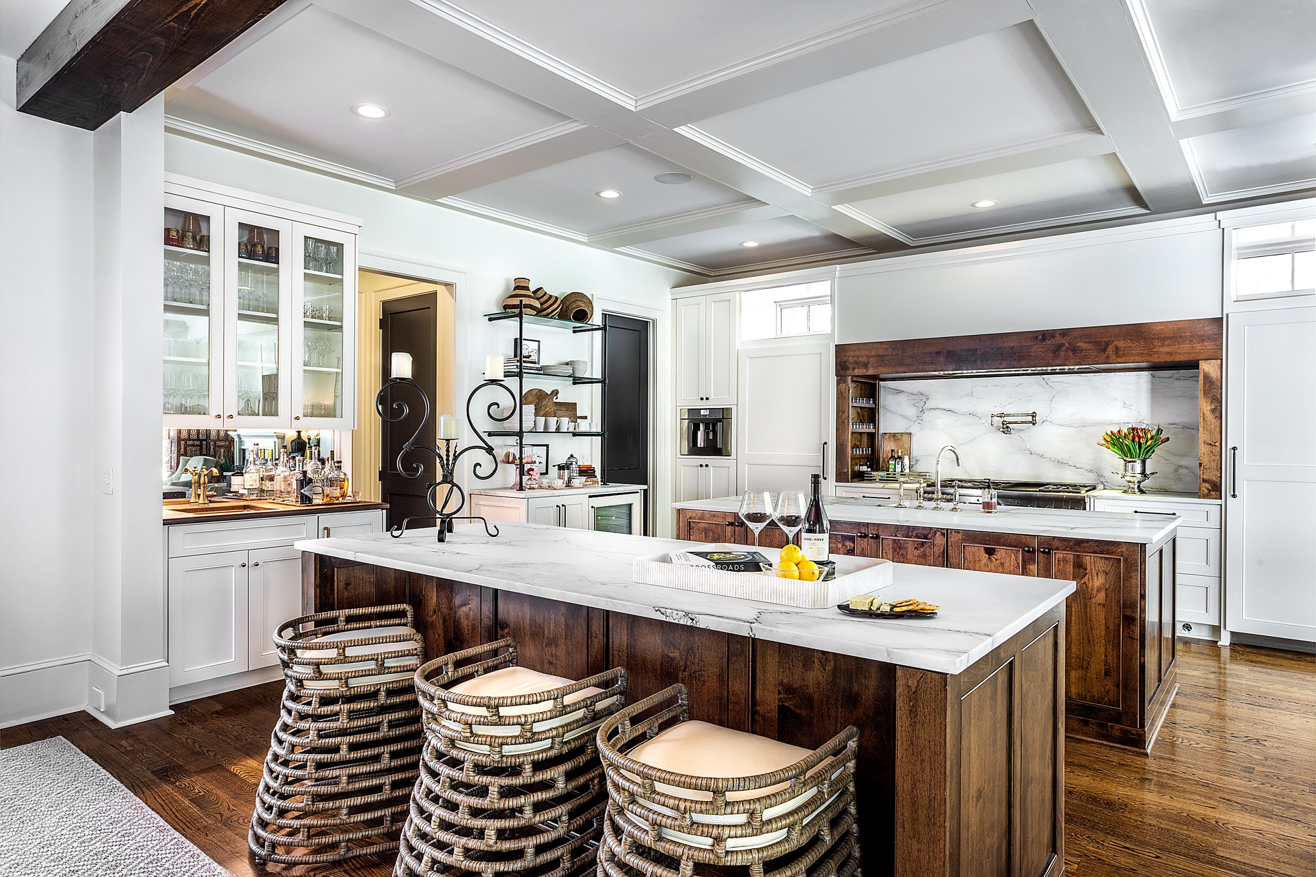 The sleek marble slabs offer Kim, who loves to cook, a clean and clear work surface. The hardwood floors, walnut islands, cooktop surround, and ceiling beams warm the space. Palechek barstools add sophisticated flair and elegance.