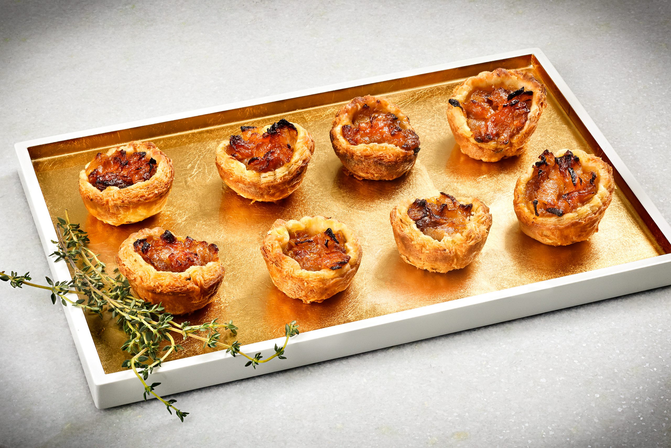 Simple flavors shine in Caramelized Onion Tartlet appetizers. You can make a larger tart with the same ingredients and serve it as a side dish or vegetarian main. Serve warm or at room temperature. Mouthwatering! Cream and gold tray courtesy of Cottage & Vine.