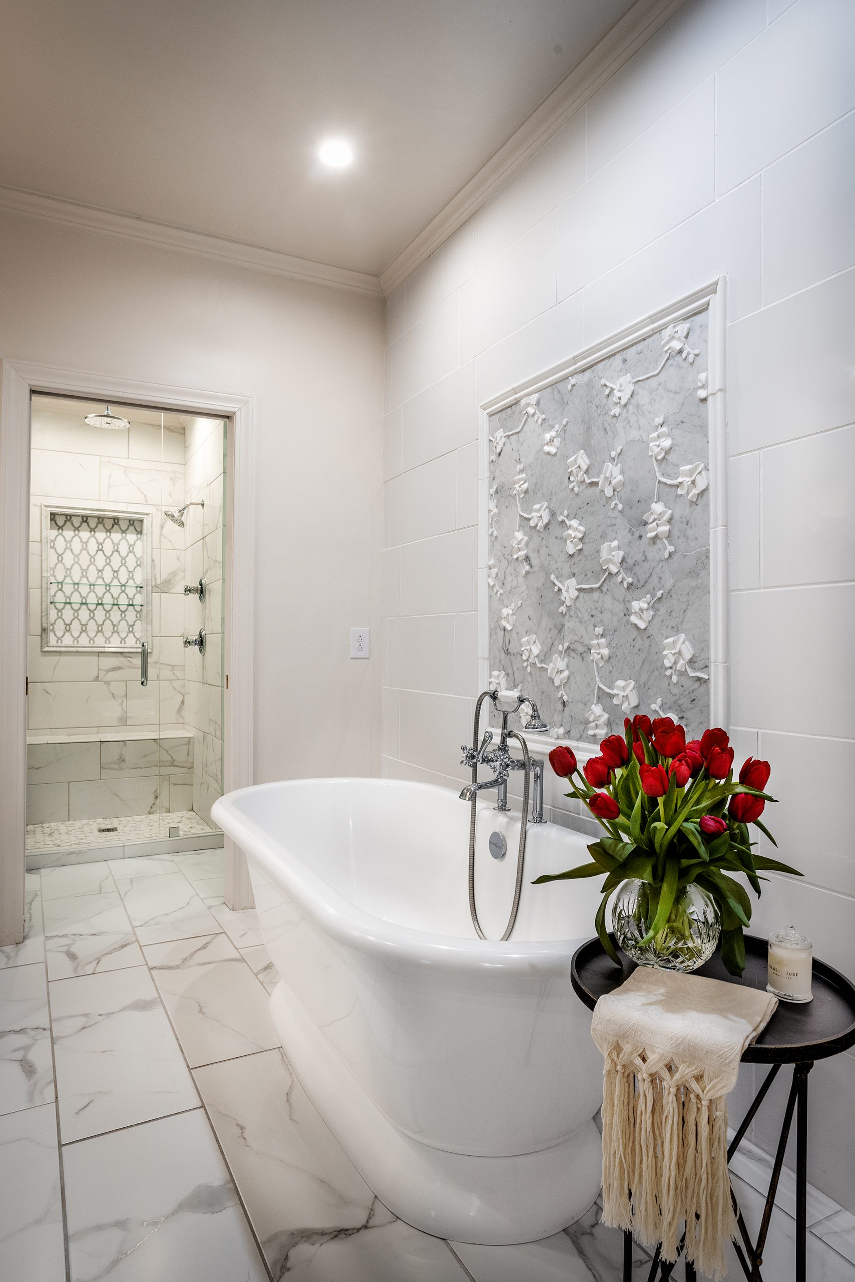 A porcelain tub is accented by whimsical custom floral wall tile by Michael Aram, all selected by Charlotte.