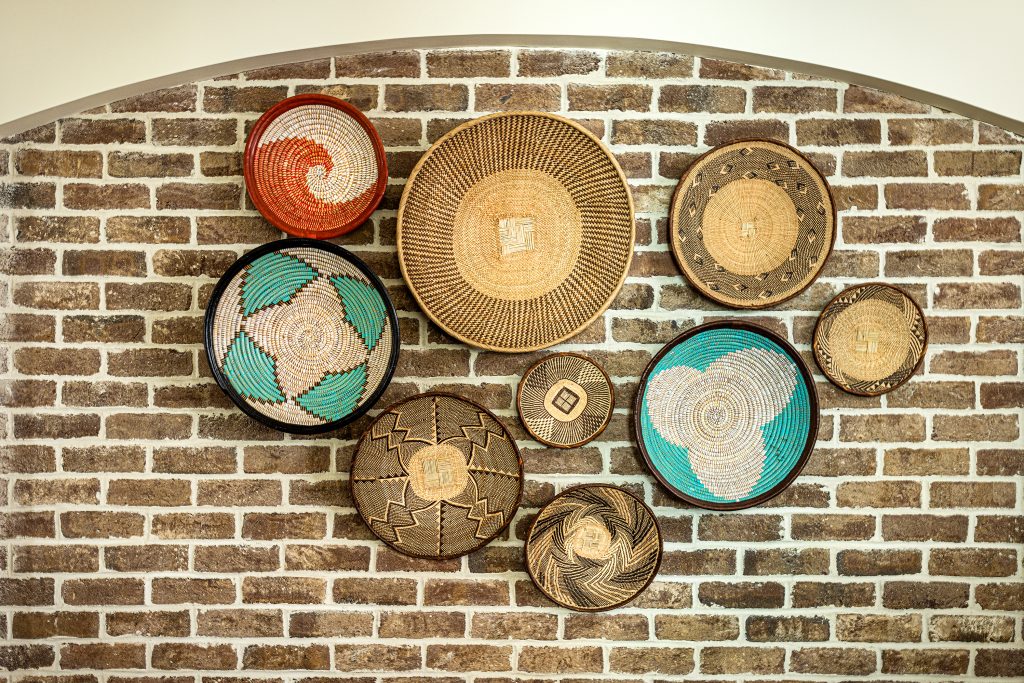 A collection of Lowcountry baskets on an exposed brick wall in the kitchen gives the room a coastal feel. 