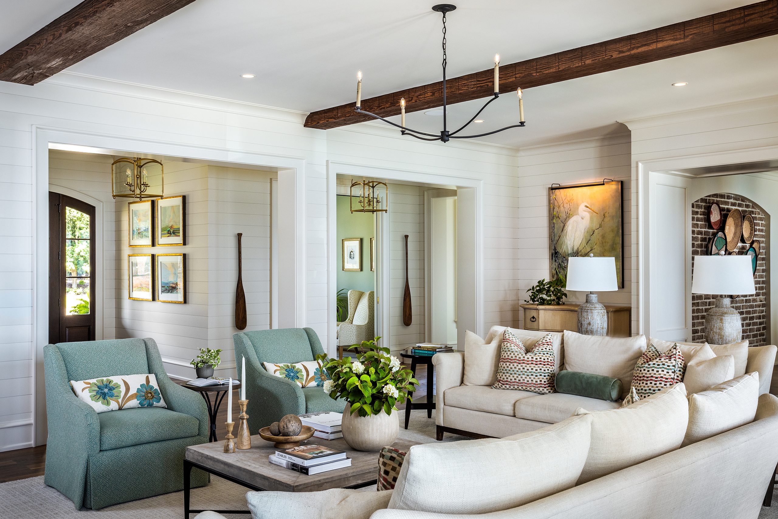The white shiplap walls are reminiscent of the original cabin that once sat by the lake, as are the exposed beams and pair of oars hanging in the hallway. The room is bright and airy, opening onto a bluestone balcony beside the saltwater pool and spa. Home styled for photography by Sheila Andrade with Black Barn Home.