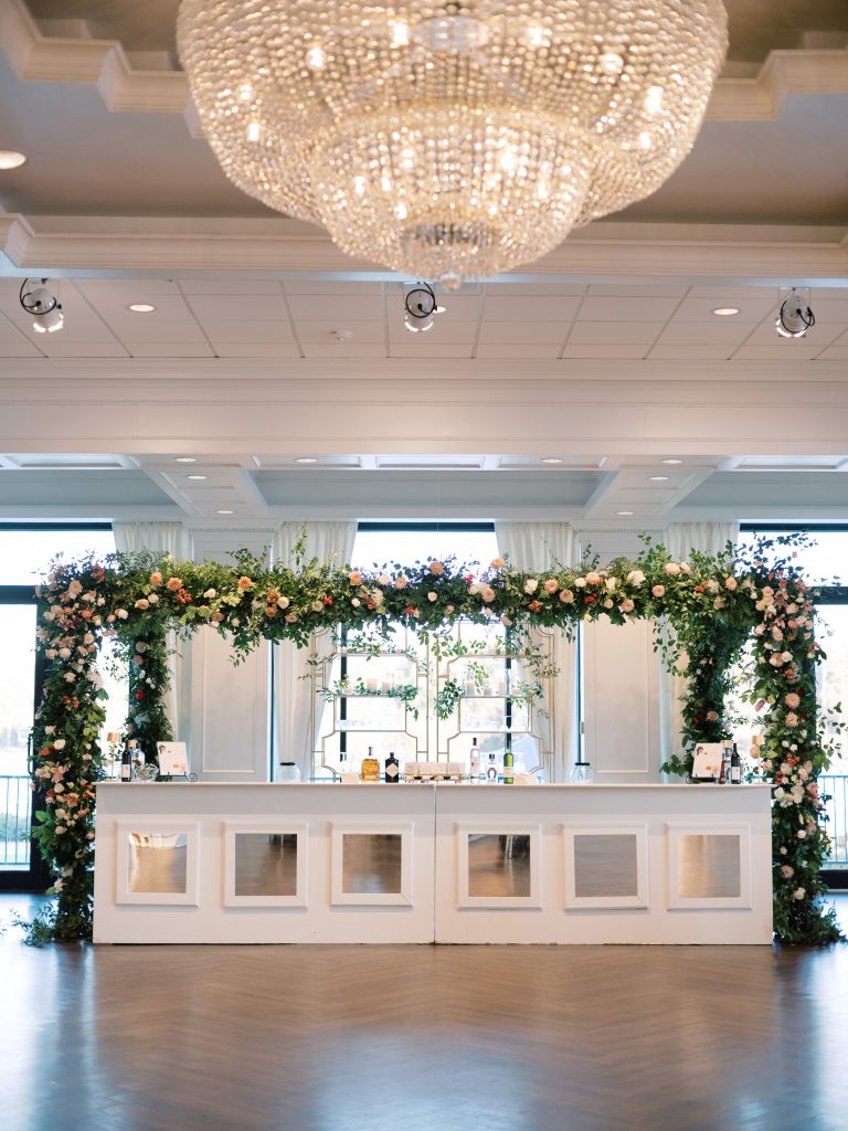 For Meg, the flowers were one of the most important aspects of the wedding. Floral designer and wedding stylist Julianne Sojourner created the spectacular floral canopy that framed the bar at the entrance to the reception, featuring white hydrangea, stock, salal, ranunculus, pink lilies, peach cremone, smilax, and camellia greenery with white, pink, and peach roses. 