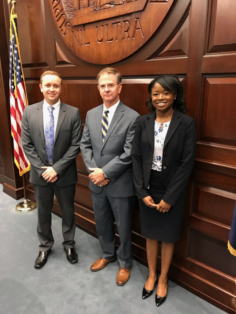 In 2019, Justice George C. James, Jr. of the South Carolina Supreme Court and Austin T. Reed, a judicial law clerk to Justice James, stand with Tyra who was Justice James’ second judicial law clerk. 