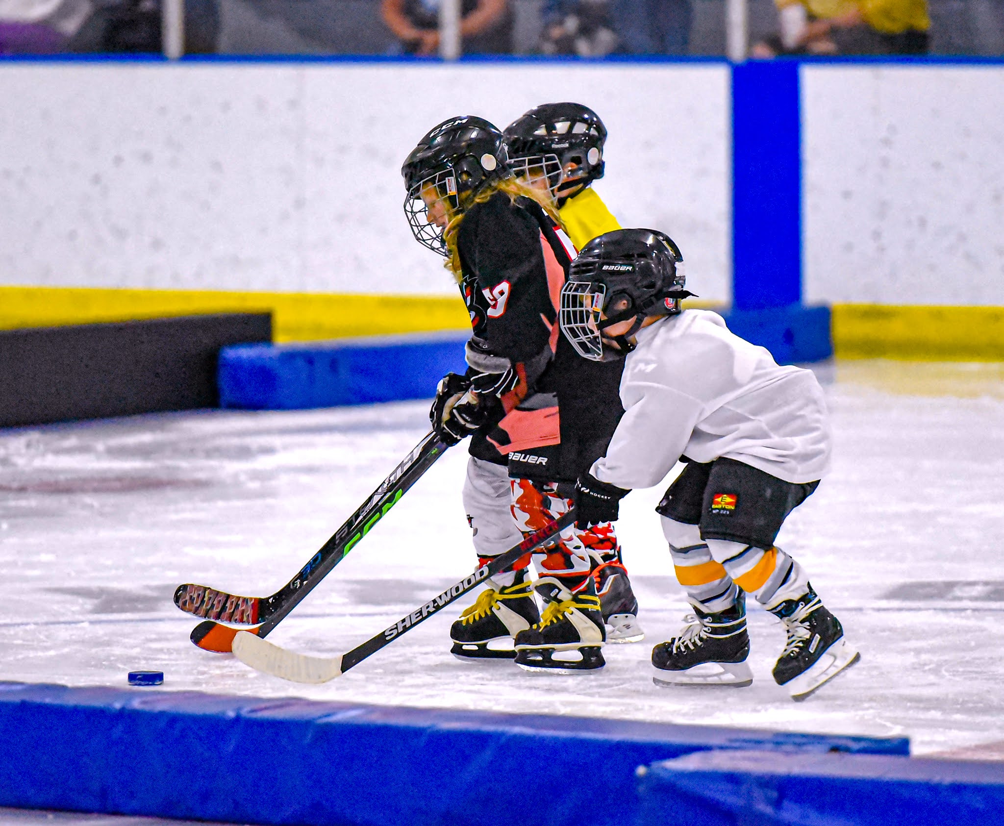 Three Cyclone 6U mini-mites fight for the puck during a Saturday morning scrimmage.