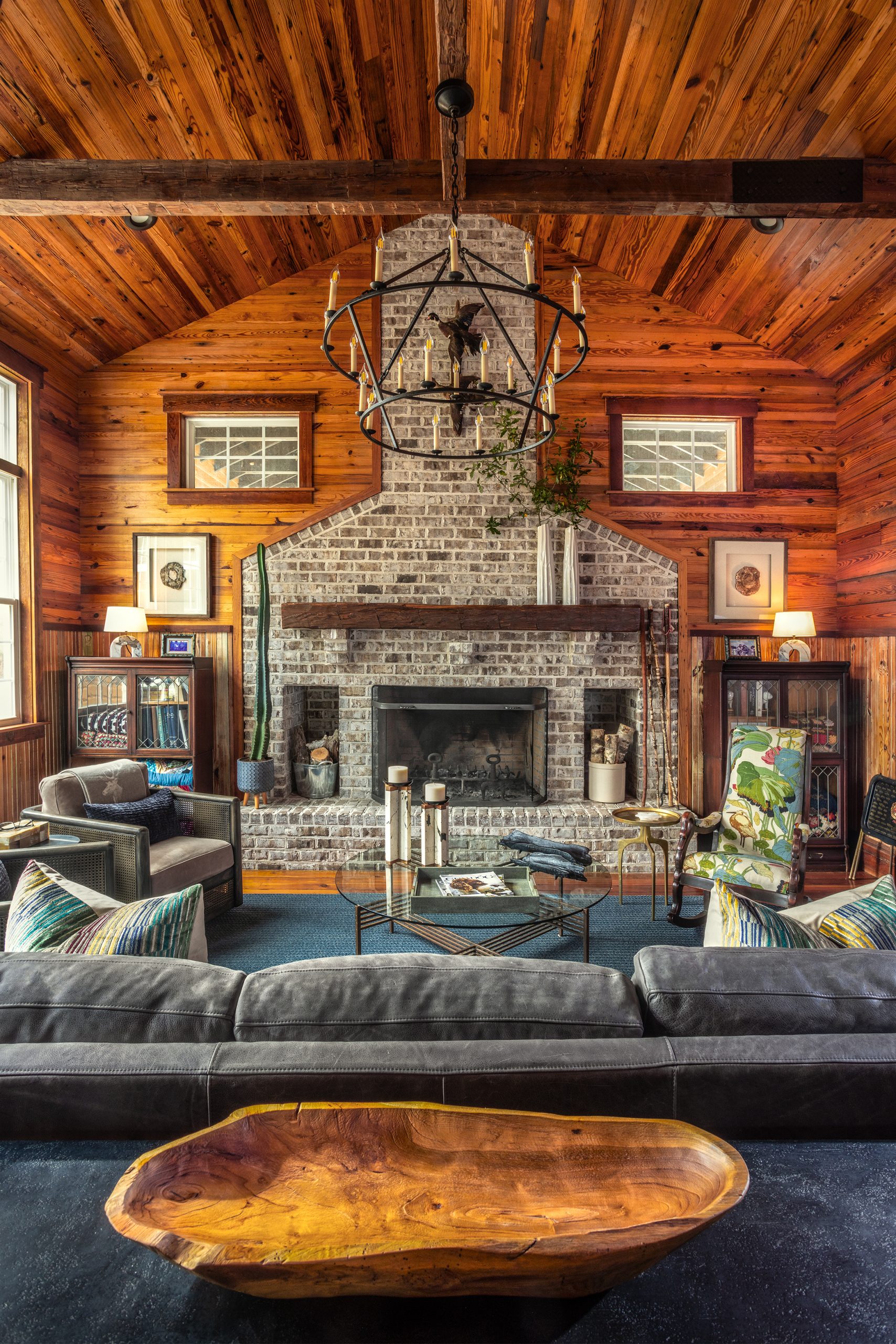 The retreat, refurbished by Steven Ford, features a traditional hunting lodge-inspired living room centered around a handsome fireplace with a mantel made from a reclaimed hand-hewn cypress beam, found in a former sharecropper’s house on the property. Mounted ducks that Ben hunted as a child are placed high above the fireplace.