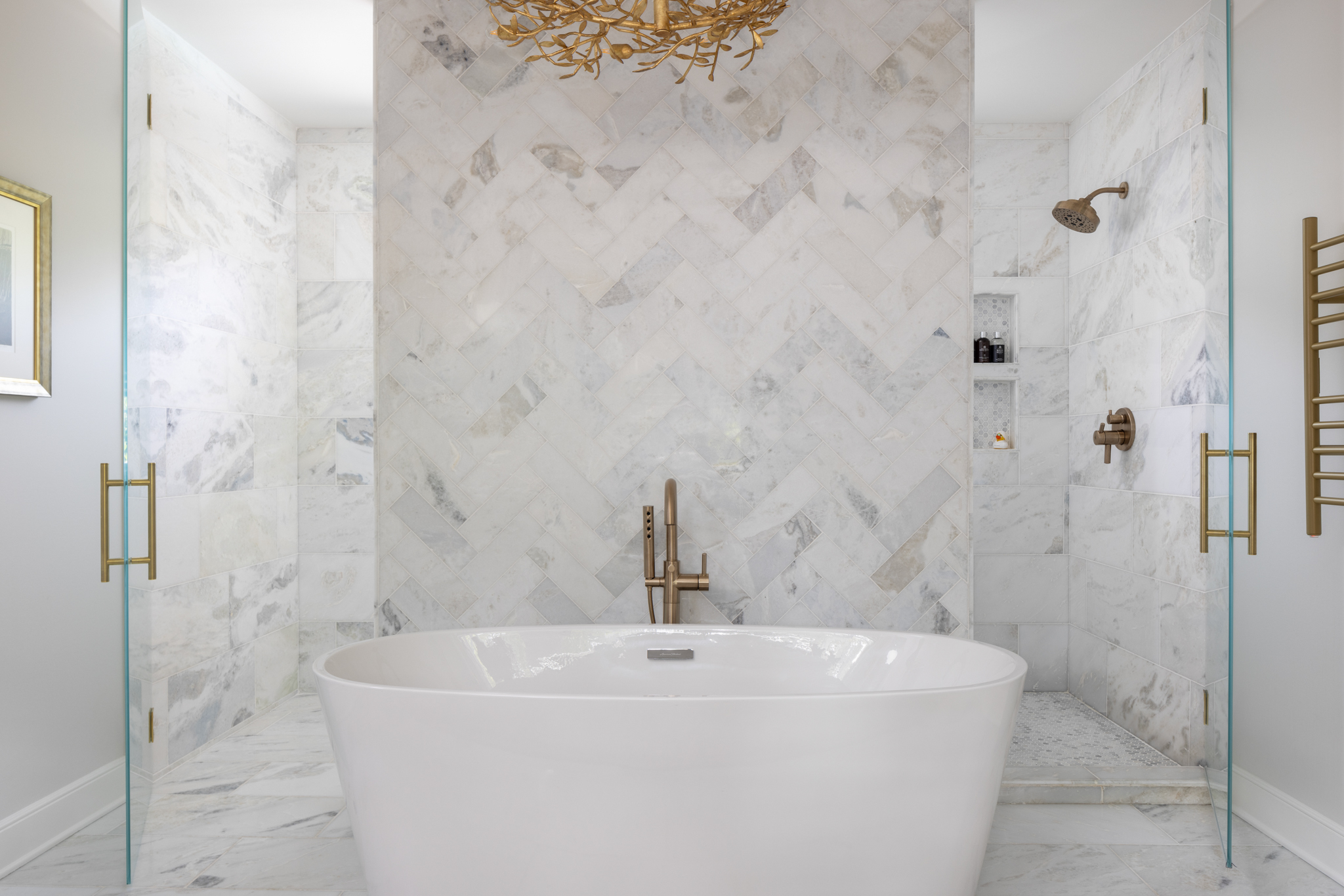  The pièce de resistance, without a doubt, is the master bathroom, a dazzling retreat exuding luxury and elegance, replete with marble flooring and tile paired with gold toned hardware. The herringbone pattern for the marble wall behind the tub is quite eye-catching!